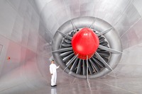 独立した建物の中にある風洞は巨大な施設だ。直径8m、カーボン製の24枚の羽根を持つファンが、1分間に最大300回転の速さで回り強風を起こす。その風はダクトを通り、実寸大の車両に当てられる。ダクト内は吸音材が敷き詰められ、騒音評価もすることができるようになっており、歩くと音が吸い込まれることに気がつく。