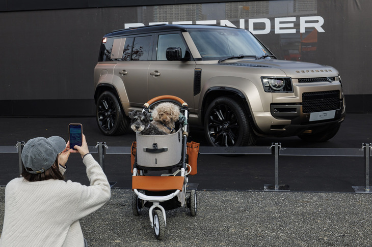 エントランス近くに展示された「ディフェンダー・オクタ」と愛犬の2ショットをスマホに収める来場者。イベント自体は参加費無料で誰でも楽しめるが、オートキャンプやブレックファーストミーティングなど、オーナー向けのエクスクルーシブプログラムが充実しているのも「DESTINATION DEFENDER TOKYO 2024」の特徴だ。
