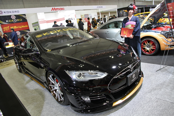 Heart Up World KOKOROの「KOKORO テスラ・モデルS」。テスラは何台か出展されていたが、この個体はオリジナルのエアロキットを装着。ボディーカラーは仏壇を思わせる黒と金、コンパニオン嬢も純和風というより外国人がイメージするキモノ姿という感じで、ちょっぴりミステリアスな雰囲気。