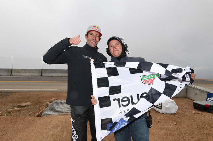 パイクスピークでは、チェッカーを受けたドライバーたちがフラッグマンと記念撮影したり、チェッカードフラッグにサインをしたりする。「ポルシェ・ケイマンGT4」で参戦したトラビス・パストラーナ（写真左）もこの習慣に応じたひとり。アメリカンモータースポーツらしいワンシーンだ。