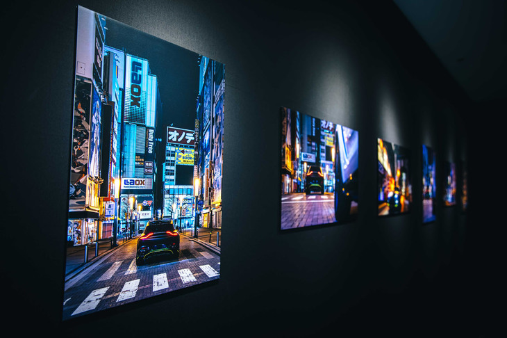 会場を飾る、東京の街なかを行く「アストンマーティンDBX707ミッドナイト ポディウムエディション」の写真。