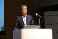 サービス誕生の経緯について説明する、電通の大久保裕一執行役員。電通では広告代理業で培ったノウハウを生かし、「広い意味で顧客をつなぐサービスを提供したい」と述べた。