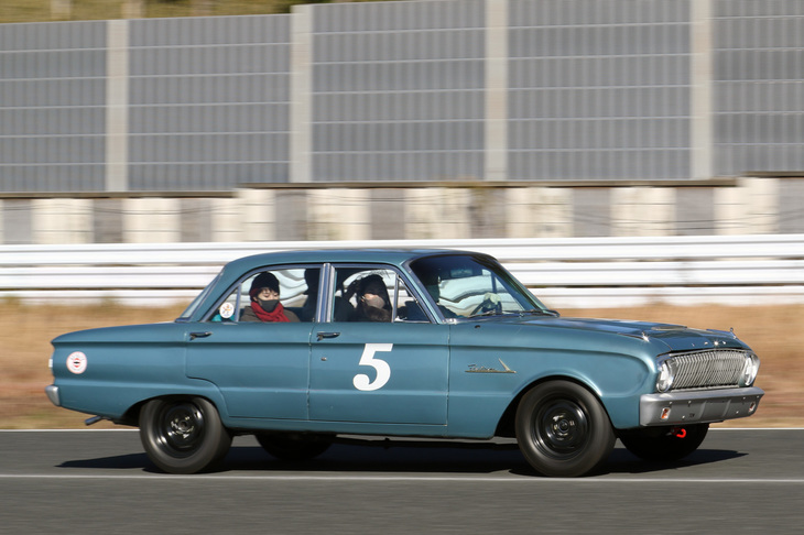 グリッドガールを乗せて走る1962年「フォード・ファルコン」。初代「マスタング」のベースにもなった米国フォードのコンパクトカーだが、英国のツーリングカーレースにも「スプリント」と名乗るクーペが出走していた。この個体は、2020年に日本公開された映画『フォードvsフェラーリ』のフォード工場のシーンで、ラインに並べるためにかき集められたうちの1台というからびっくり。