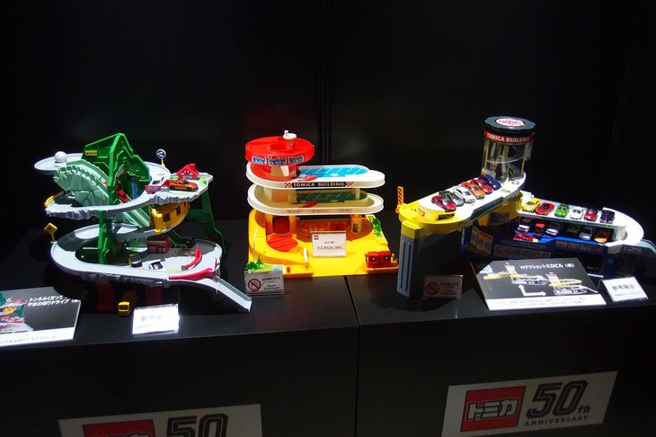 ファンにはたまらない“基地系”の製品。1971年発売の「トミカビル」（写真中央）をはさんで、左が開発中の「トンネルくだって！ やまのぼりドライブ」（仮題）、右が同じく開発中の「Wアクション トミカビル」（仮題）。