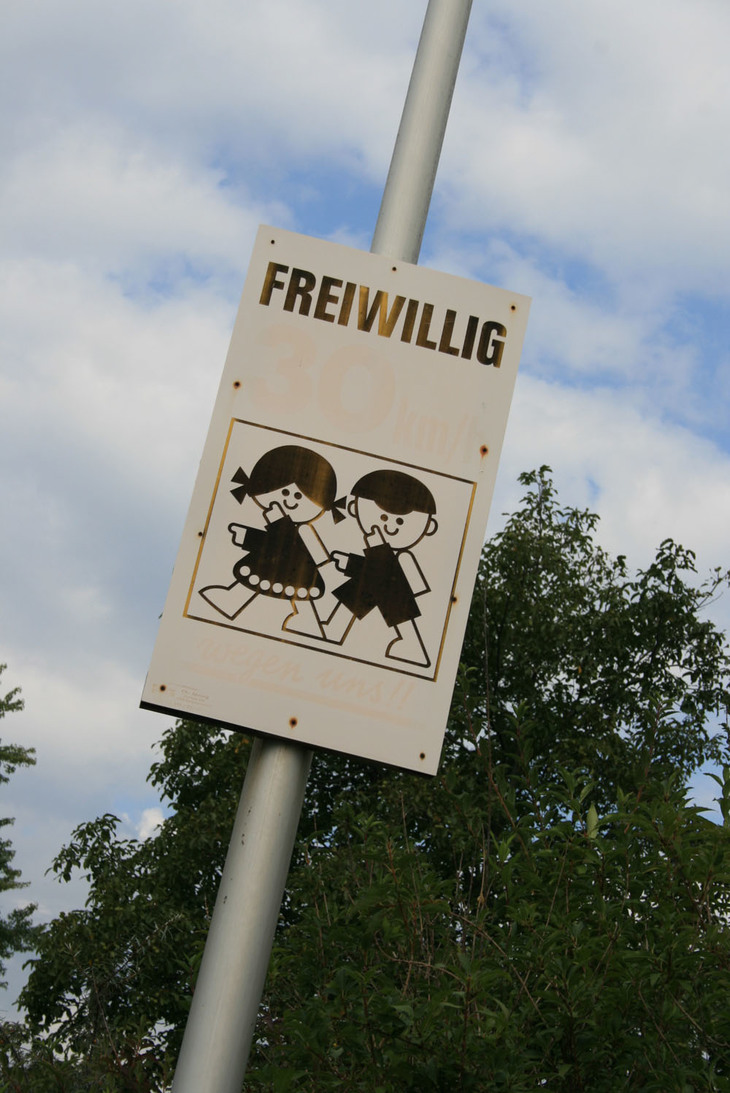 写真2。スイスにて。「私たちがいるから、すすんで減速して」を訴えるサイン。