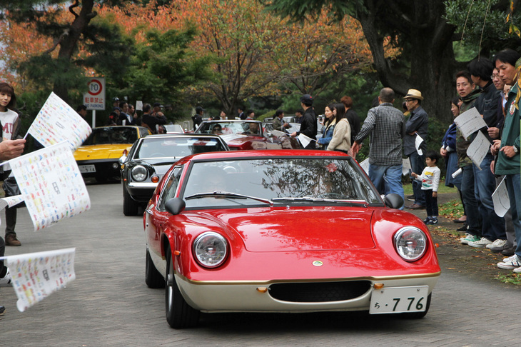 表彰式に続く閉会式終了後、参加車両は地元新聞社から配られた小旗を振るギャラリーに見送られ、パレード形式で退場する。1969年「ロータス・ヨーロッパS2」にJPSカラーの1974年「同スペシャル」が続く。