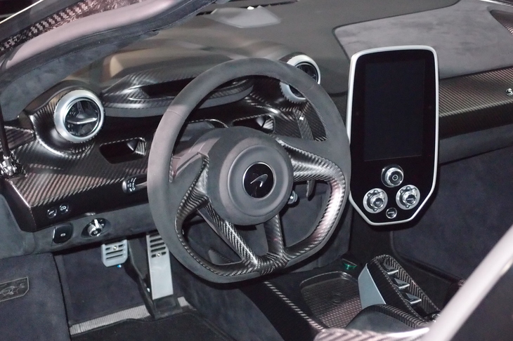 カーボン地がむき出しのコックピット周辺部。センターコンソールには縦型のディスプレイと車両セッティング用のダイヤルが用意される。