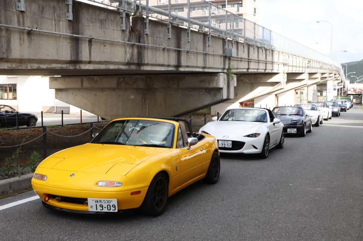 会場へと向かうロードスターの列。周辺住民に配慮して、試験場への入場はすべて左折のみに……。住人の方々が、沿道で全国より集まるロードスターを鑑賞する姿も見受けられた。マツダが地域で愛されている企業であることが感じられた瞬間であった。