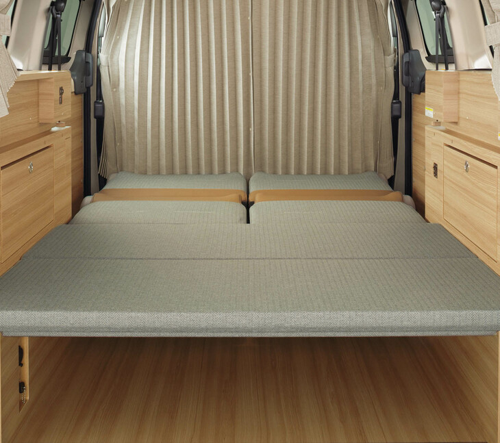 「2 in 1シート」（後席）とボードを組み合わせ、ベッドルームモードとした「NV200バネットMYROOM」の車内。この就寝スペースの広さは1840×1200mmで、ベッドのフロアから天井までの距離は953mm。ベッド下には高さ260mmの空間が確保される。