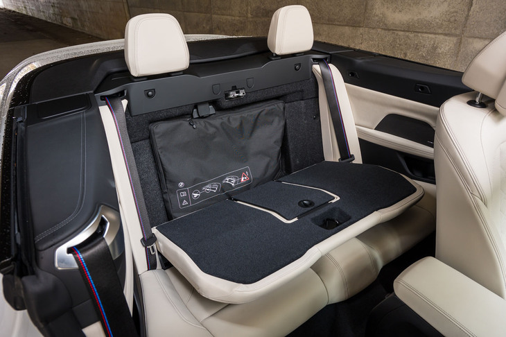 ヘッドレストを残して背もたれを前に倒せる。これでトランクスルーにできるが、そこに折りたたんだウインドディフレクターが収納されているのが見事だ。