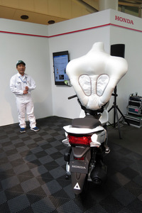 小型スクーターへの装着を想定した新開発の二輪車用エアバッグ。ユニークな形状は、さまざまな状態での四輪車との接触から、ライダーを守るために考案されたものだ。