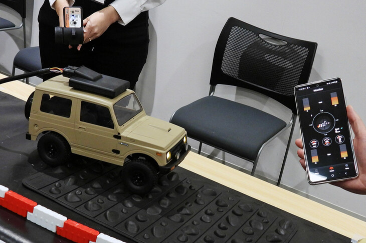 「アクトライド」を装備したRCカーによる、デモンストレーションの様子。デコボコ道を走ると、減衰力の変化などがスマートフォンの画面に表示される。