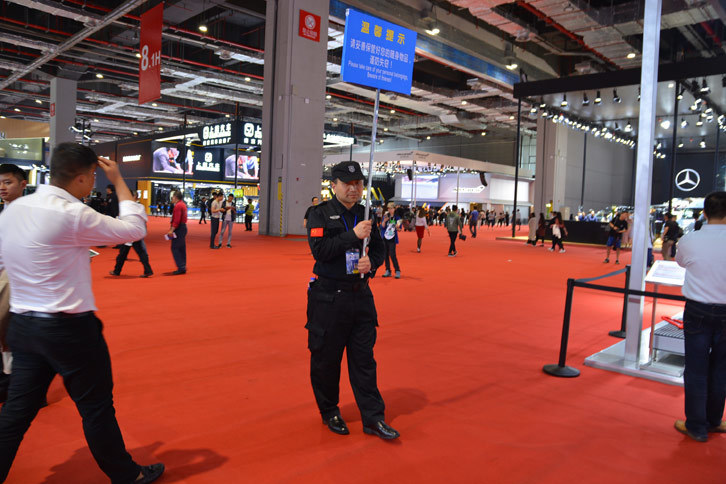 上海モーターショーの名物はプラカードを持った公安（治安維持の警官）。プラカードには「荷物に注意」と書かれている。このほかにも、会場には非常に多くの公安が配置されている。