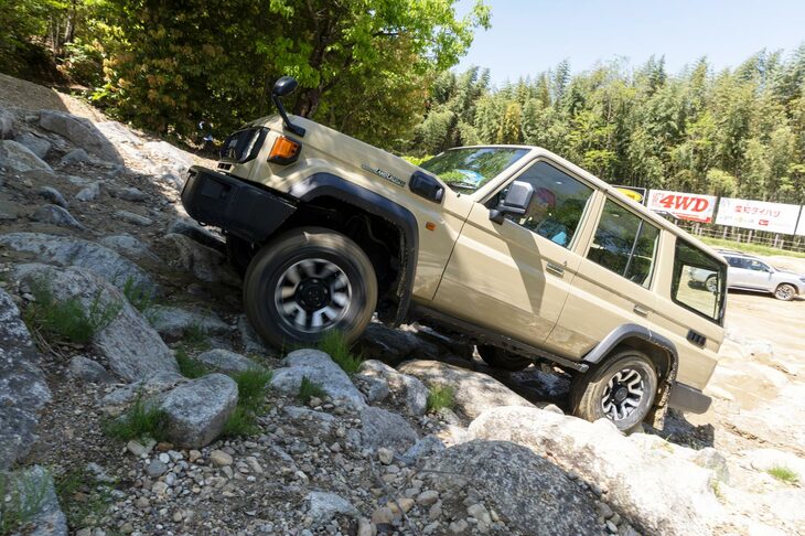 勢いをつけて岩場を乗り越える「ランドクルーザー“70”」。同車には、悪路において自動で一定速走行を行う「クロールコントロール」などの機能は用意されておらず、ドライバーは自らの手足でクルマを操る必要がある。
