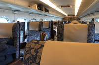 「800系」の客室内部。「客室を仕切る妻壁は金沢の職人の金箔（きんぱく）で、仏壇職人の木彫や博多織職人の作品を金箔の額縁に入れて飾ってます。シートも自然木で、車両ごとにデザインも違う。洗面にはイグサの縄のれんを下げました」と水戸岡さん。