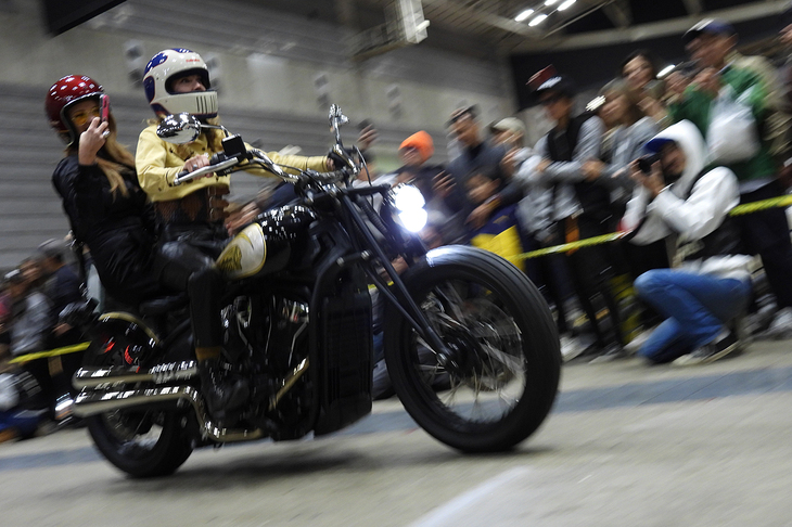 会場の“花道”を通って著名なカスタムカー／カスタムバイクやゲストが登場する「RIDE IN SHOW」より。自身の手になる新型「インディアン・スカウト」のカスタムバイクに乗って登場する、カスタムビルダーのブリトニー・オルセン氏。