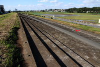 全長350mにおよぶグランドスタンド。赤い矢印の部分に、2016年5月に開設80周年を記念して多摩川スピードウェイの会と川崎市によって埋め込まれたプレートがある。