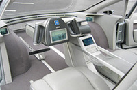 
	ハイ・ワイヤーの運転席。センターパネルに、P-R-N-Dのスイッチが配され、Dレンジを選べば発進できる。足元にペダルはなく、電動で位置調整できるフットレストがあるのみ。サイド＆バックミラーの代わりに、カメラと液晶モニターを装備する。
	 