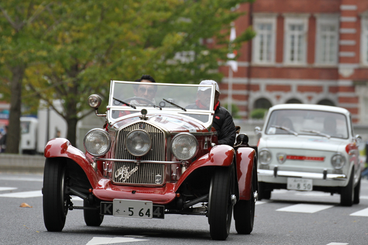 東京駅中央口交差点と和田倉門交差点を結ぶ、通称行幸通りを行く1929年「アルファ・ロメオ6C 1750SS」。モータースポーツでも大活躍した、戦前のアルファの傑作のひとつ。続くのは「フィアット850ベルリーナ」をベースにした1965年「フィアット・アバルト OT850」。