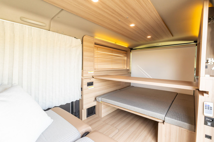 上の写真で右の壁面にあったボードを下ろし、テールゲート手前のロールスクリーンを展開するとシアタールームモードに。後ろ向きにしたシートからグレーの部分に足を伸ばして座れる。