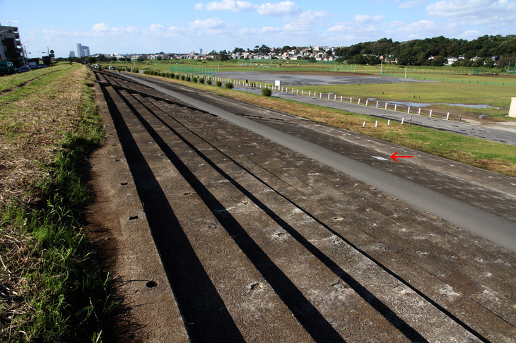 全長350mにおよぶグランドスタンド。赤い矢印の部分に、2016年5月に開設80周年を記念して多摩川スピードウェイの会と川崎市によって埋め込まれたプレートがある。