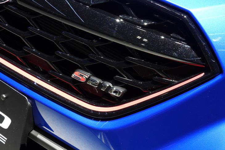 クリスタルブラック・シリカ塗装が施された「S210プロトタイプ」のフロントグリル。STIでおなじみのチェリーレッドストライプがあしらわれ、「S210」のエンブレムが輝く。