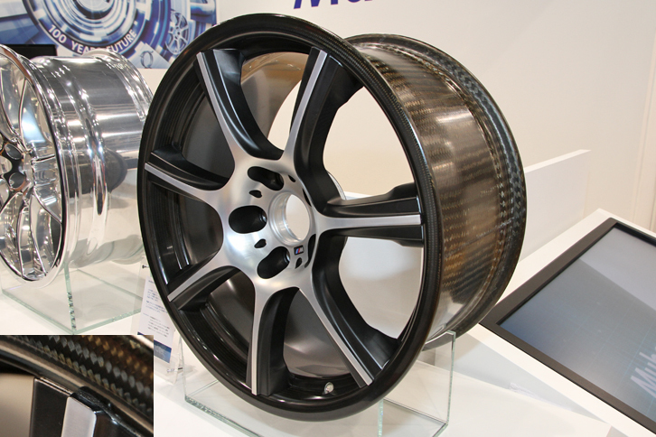 ムベアが出展していた、「BMW M4」にオプション設定されている、アルミ製スポークとCFRP製リムからなるハイブリッドホイール。鋳造アルミホイール比で40％、鍛造アルミホイール比で20％の軽量化を達成。解説員に「今日の超偏平タイヤだと、タワーパーキングの入出庫などでもホイールを傷つけやすいので、カーボン面を擦らないか不安……」と話したところ、「そういう事態を想定して、スポーク部分をリム表面より若干出っ張らせています」とのこと（写真左下参照）。