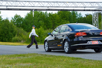 自動運転中の車両の前を歩行者が横切る。速度が低いときには緊急ブレーキが作動して事故を回避。