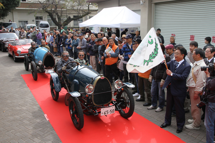 80台近くが参加したラリーのスタート風景。スターターを務めた桐生市長の荒木恵司氏がフラッグを振り下ろし、車齢95年の1924年「ブガッティT13ブレシア」がスタートしていく。続くのは1922年の同モデル。