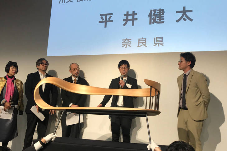 サポートメンバーの川又俊明さん（右）から「注目の匠」に選ばれたのは奈良県代表の木工作家、平井健太さん（右から2番目）。杉材を使った曲木の技術が高く評価された。