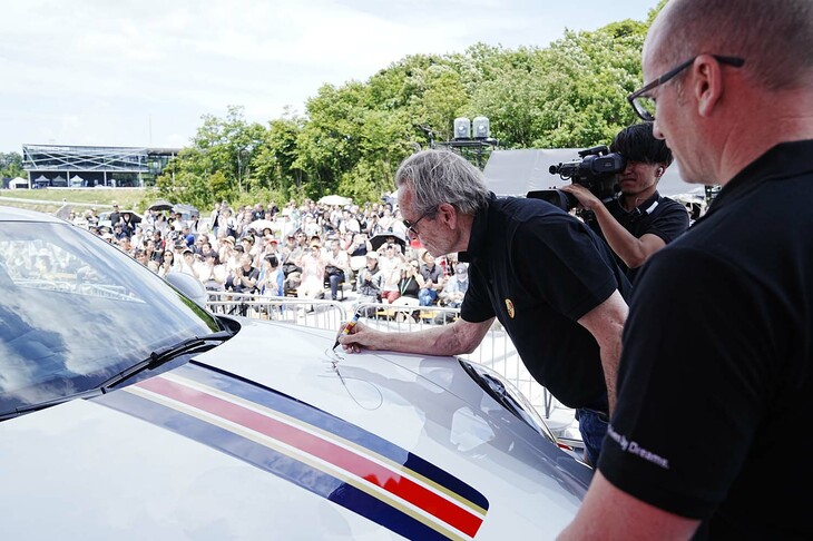 「911ダカール」のボンネットにサインするジャッキー・イクス氏。