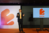 EMTAについて説明する、EMTの何暁慶CEO。「E」の字をかたどったロゴマークについては、「おだやかなデザインで気に入っています。右肩上がりなイメージなのもいい」と感想を述べた。