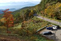 展望台へ続く小道から駐車場を見下ろす。……いや、自分が来たときにはすいていたんですよ。もっと端に止めておけばよかった（汗）。