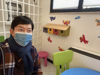 待合室にて。子ども用の椅子とテーブルで、執筆記事の校正をしながら、順番を待つ筆者。