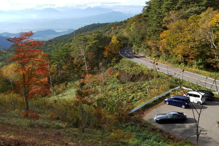 展望台へ続く小道から駐車場を見下ろす。……いや、自分が来たときにはすいていたんですよ。もっと端に止めておけばよかった（汗）。