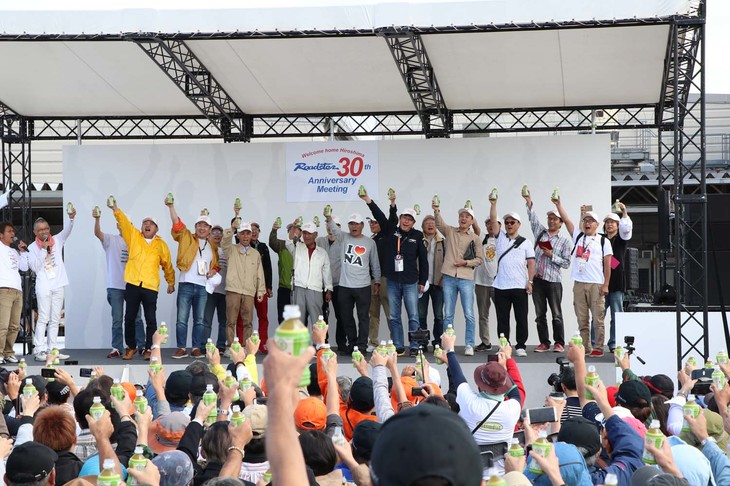 ロードスターオーナー代表として、初代NAの極初期型となる平成元年式をワンオーナーで持ち続けている人たちが登壇。その証しとなる白い帽子は、初代から3代目まで開発を指揮してきた貴島孝雄さんから手渡されたものだ。参加者全員でお茶のペットボトルを片手に乾杯し、ロードスターの30歳を祝った。