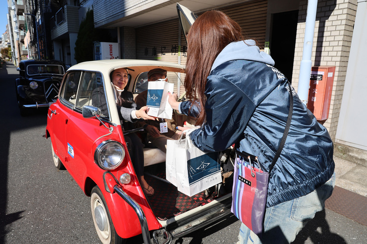 ドアを開けて、柳橋手前にある小松屋謹製のおみやげ（つくだ煮）をもらっている1959年「BMW 600」。「BMWイセッタ」から発展した4人乗りの四輪ミニカー。