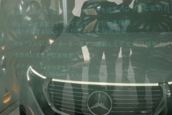 駐車スペースと居住空間をガラスドアで仕切ったところ。ガラスには「EQC」の車両概要が表示されている。