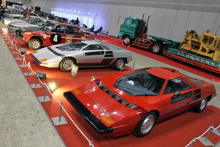 特別展示車両。手前から「童夢P2」「童夢・零」、そして1970年のサファリラリー優勝車である「ダットサン・ブルーバード1600SSS」など。童夢・零は1978年のジュネーブショーで初公開された童夢オリジナルの国産スーパーカー。全長3980mm、全幅1770mm、全高980mmというコンパクトなボディーに日産製L28（2.8リッター直6 SOHC）をミドシップしていたが、型式認定が取れず市販化を断念。童夢P2はアメリカ市場に向けて現地の法規に合わせたモデルだが、こちらも販売計画は頓挫した。後方に見えるのは、はたらく自動車博物館所蔵の「日野HEトラクタ」と「コマツブルドーザ」。
