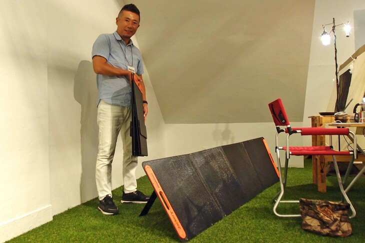 写真で床面に展開している「SolarSaga 200」は、折りたたむとこんなに薄くてコンパクト。その厚さはわずか4cmほど（収納サイズ：縦×横×厚さ＝540×625×44mm）で、展開サイズは同540×2355×25mmとなる。単結晶シリコンセルを2枚搭載し、22％という高い変換効率を実現。電力は最大200Wの大出力を確保した。単体重量は約8kg、単品プライスは8万6600円。長期間にわたってアウトドア生活に身を置くロングタームキャンパーの方にもオススメできる。