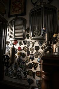 壁にはラジエーターグリルなどの自動車パーツ、さまざまなバッジがディスプレイされている。