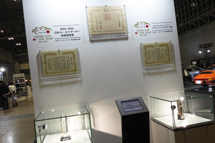 会場では、ポルシェジャパンが受けた各種表彰の展示も行われた。日本カー・オブ・ザ・イヤー部門賞のトロフィーや表彰状とあわせ、上段に飾られているのは、2025年7月に受賞した紺綬褒章の表彰状だ。さまざまな社会貢献活動が評価されての受賞で、自動車インポーターとしては初めてのことだった。