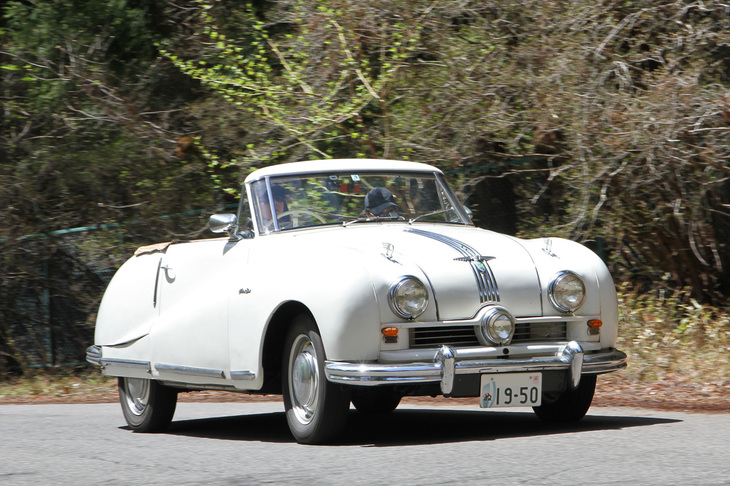 女性ペアがドライブする1950年「オースチンA90アトランティック コンバーチブル」。