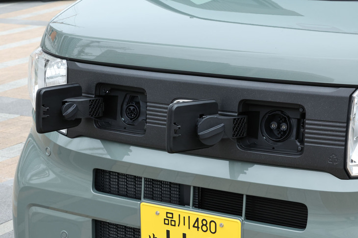 「N-VAN e：」の充電口は、フロント左右のヘッドランプ間に設置されている。日常使用における使いやすさにこだわった高さと角度を追求したという。向かって左が200Vの普通充電口、同右がCHAdeMO規格に対応する直流急速充電口。フロントの装飾パネルには、バンパーのリサイクル素材を使用している。