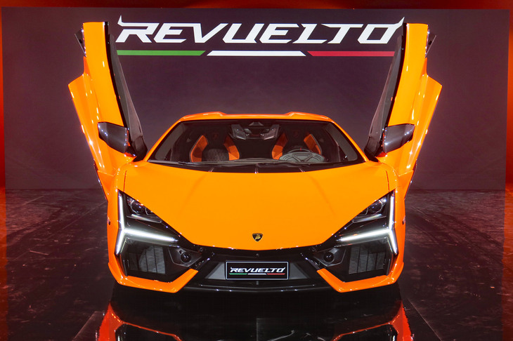 日本での発表会より、シザースドアをご開帳する「レヴエルト」。　
	清水「いやホント、最近のスーパーカーは名前を覚えられないよ」　
	ほった「……まぁ、その点については先代の『アヴェンタドール』も最初は一緒でしたけど」