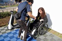 「車いす連結タイプ」を、実際に車いすに取り付けているところ。今回はスタッフにサポートしてもらったが、製品化までには車いすユーザーが自分で簡単に装着できるよう改良するという。