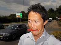 国道沿いでやって来るクルマを数える大矢アキオ。