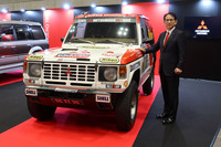 初代「三菱パジェロ」のダカールラリー総合優勝車と、岸浦惠介 三菱自動車代表執行役員兼COO。