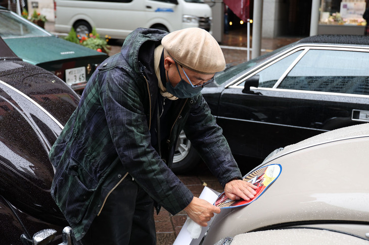 雨にぬれたボディーを拭きながら、ゼッケンを貼る参加者。