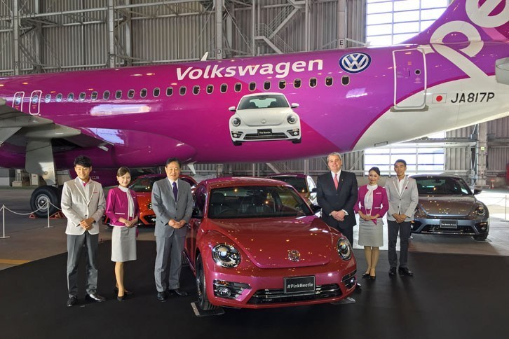 限定車「#PinkBeetle」を中心に、ピーチの井上慎一代表取締役CEO（向かって左）と、VGJのティル・シェア代表取締役（同右）。
